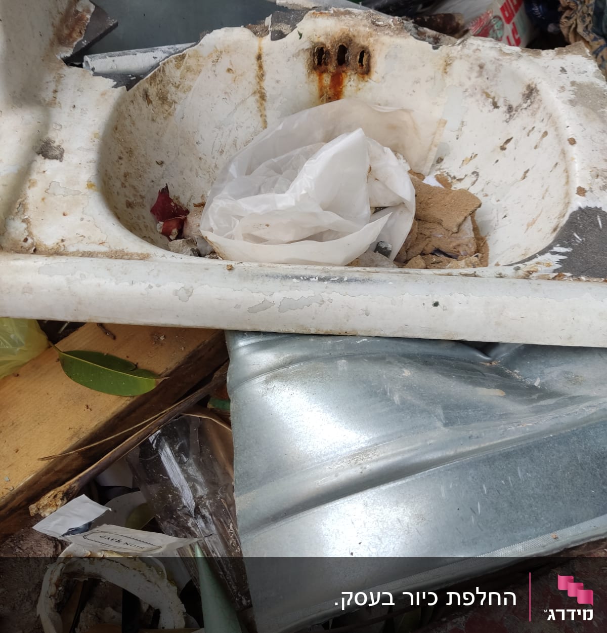 A rusty, broken sink with debris and pipes.